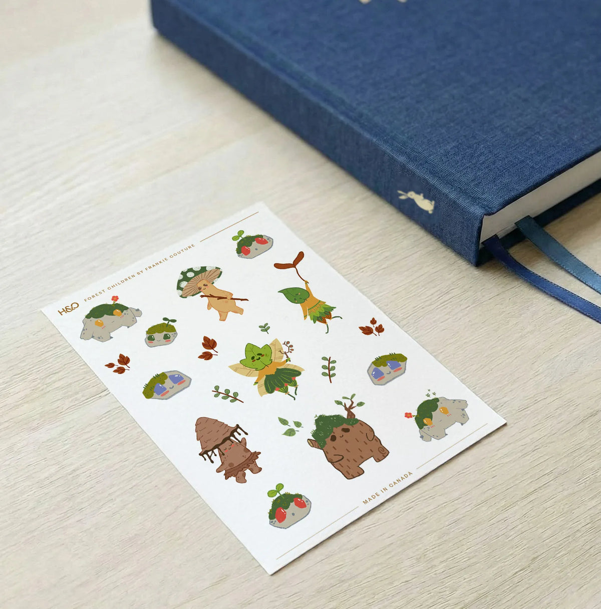 Forest Children sticker sheet by Frankie Couture shown with a notebook